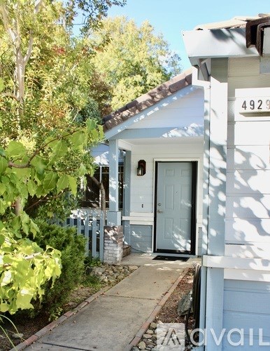 A white house with a blue door and a white fence.