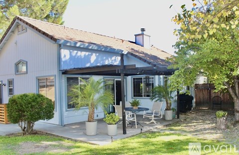 A house with a blue awning and a patio with chairs and a table.