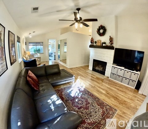 A living room with a black leather couch and a fireplace.