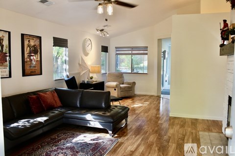 A living room with a black leather couch and a rug.