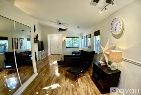 A living room with a black couch and a ceiling fan.