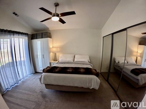 A bedroom with a large bed and a ceiling fan.