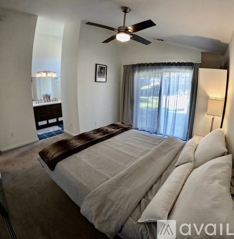 A bedroom with a large bed and a ceiling fan.