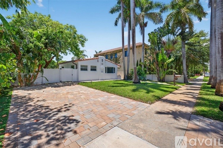 A house with a driveway and palm trees in front.