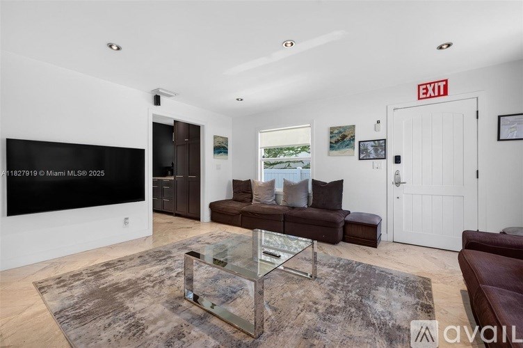A living room with a glass coffee table and a flat screen TV mounted on the wall.