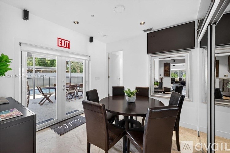 A dining room with a table set for four and a view of a pool through a glass door.