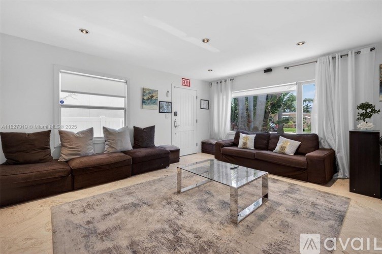 A living room with a brown couch, a glass coffee table, and a rug.