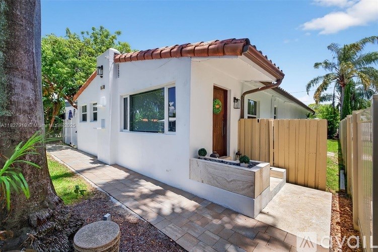 A white house with a red tile roof and a wooden fence.
