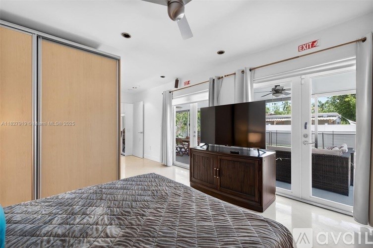 A bedroom with a bed, a television, and a sliding glass door.