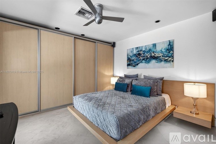 A bedroom with a bed, a ceiling fan, and a painting on the wall.