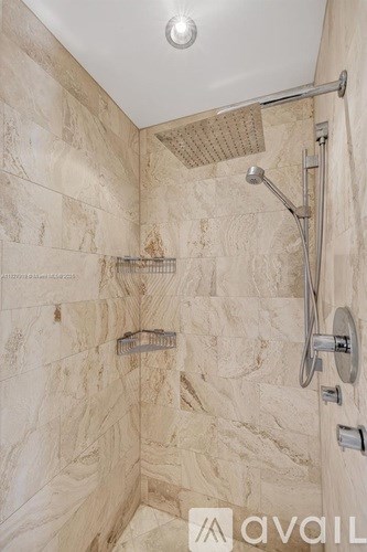 A shower area with a tiled wall and a shower head.