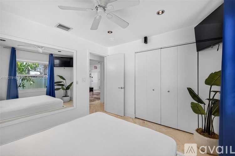 A bedroom with a bed, a ceiling fan, and a cabinet.
