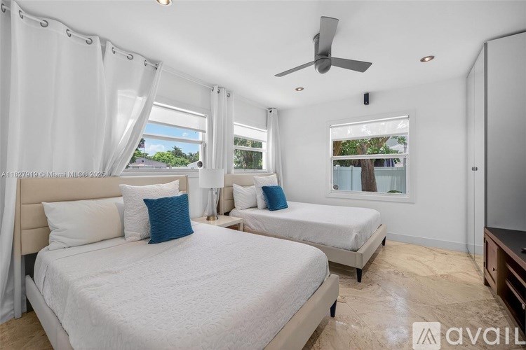 A bedroom with two beds and a ceiling fan.