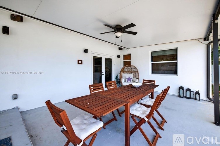 A wooden table with chairs is set up in a room with a ceiling fan.