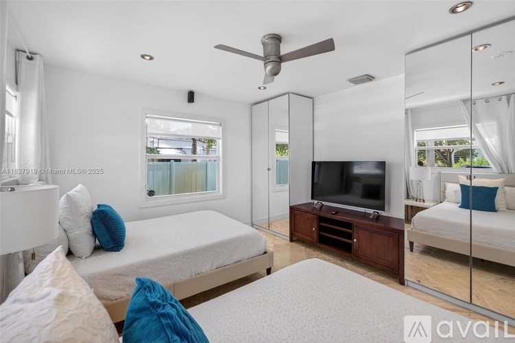 A bedroom with a bed, a television, and a mirror.