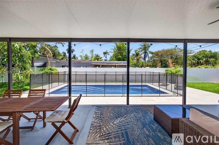 A patio with a table and chairs overlooking a pool.