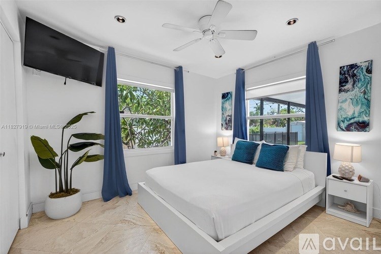 A bedroom with a large bed, a ceiling fan, and a television mounted on the wall.