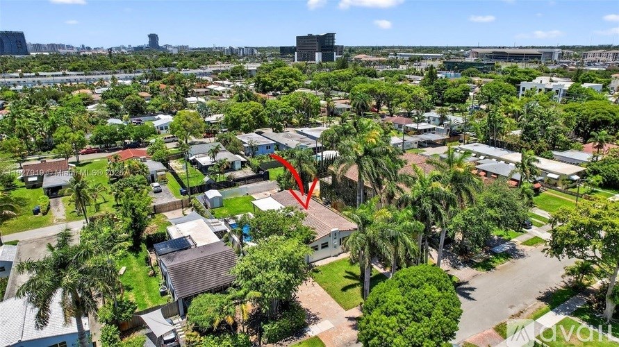 An aerial view of a residential area with a red arrow pointing to a specific house.