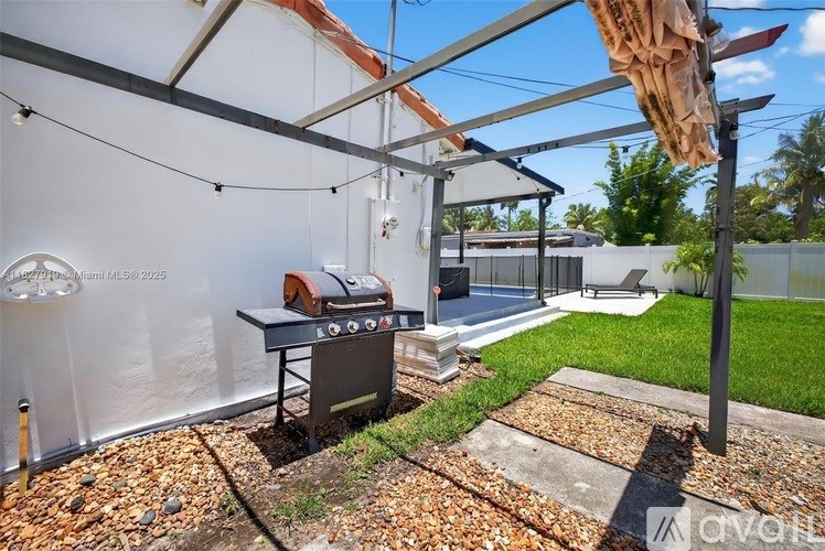 A barbecue grill is set up under a canopy in a backyard.