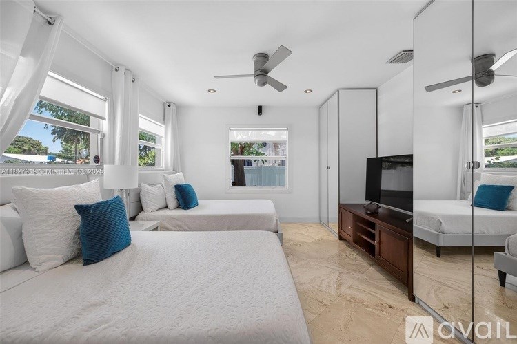 A bedroom with two beds and a television.