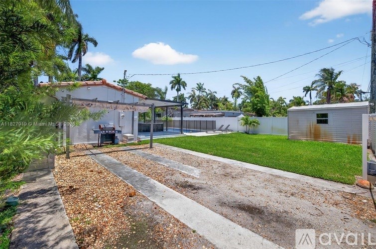 A backyard with a concrete path and a small building.