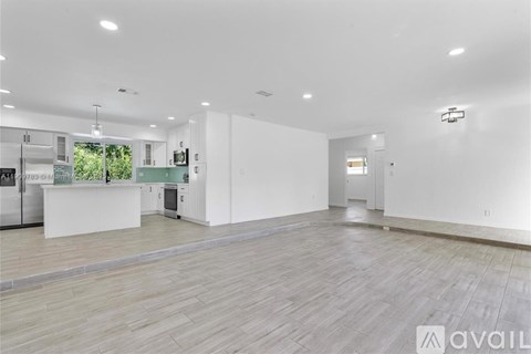 A spacious kitchen with white cabinets and a wooden floor.