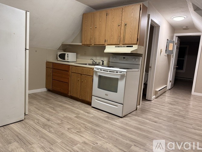 A kitchen with a white fridge, a white oven, and wooden cabinets.