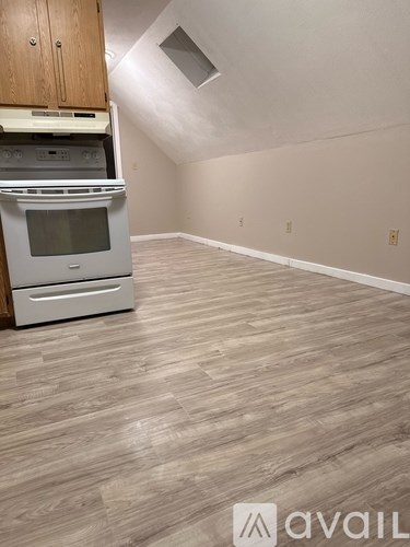 A kitchen with a stove and oven is in the corner of a room with wood flooring.