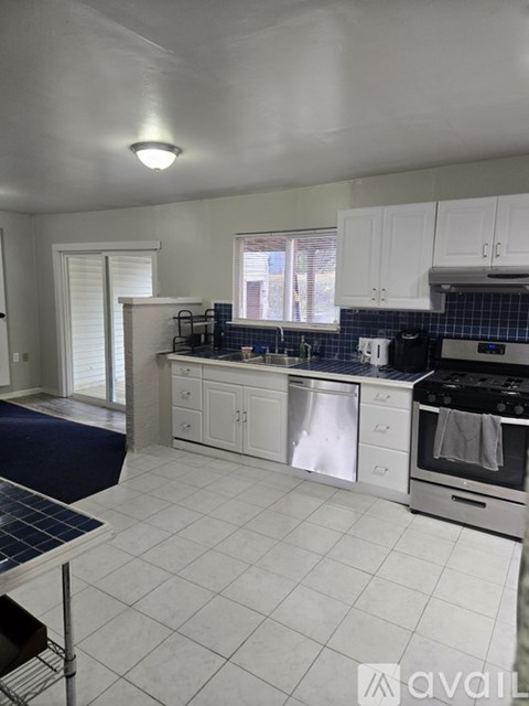 A kitchen with white cabinets and a blue tile backsplash.