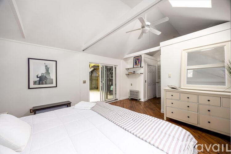 A bedroom with a bed, dresser, and a ceiling fan.