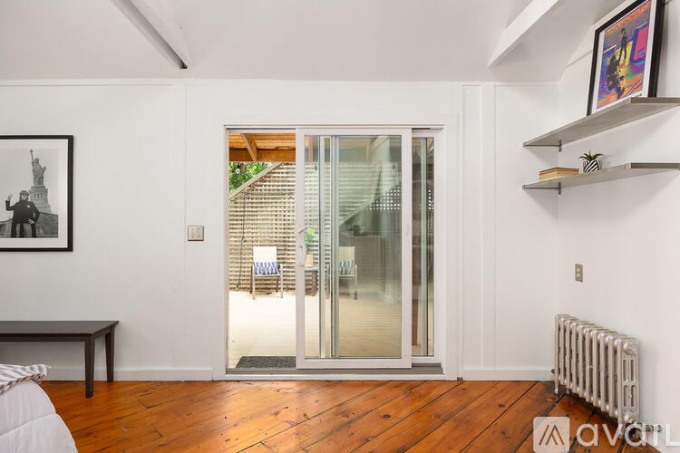 A room with a wooden floor and a glass door leading to a balcony.