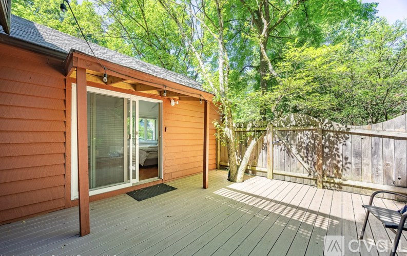 A wooden deck with a bench and a sliding glass door leading to a room.