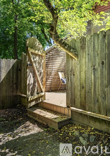 A wooden gate in a garden leads to a deck.