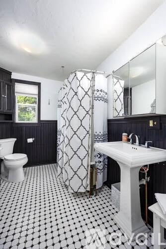 A black and white bathroom with a toilet, sink, and shower.