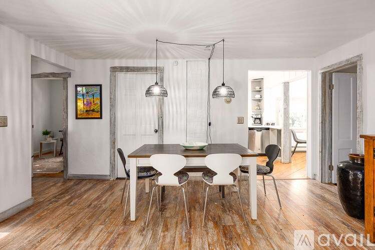 A dining room with a wooden floor and white walls.