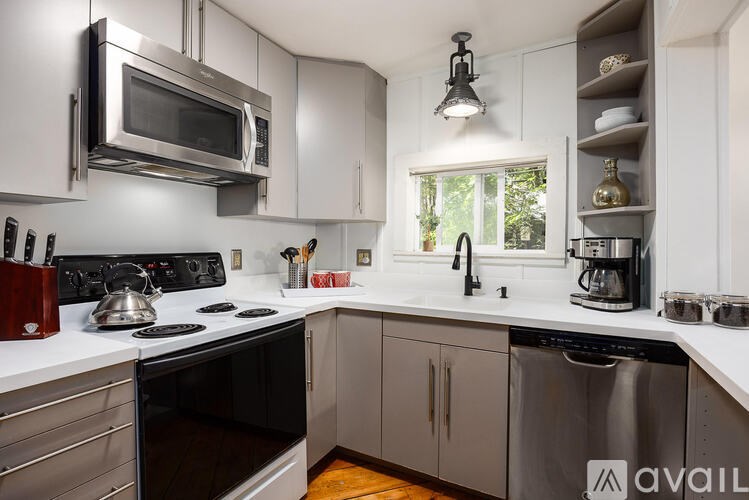 A kitchen with a stove top oven, microwave, and a window.
