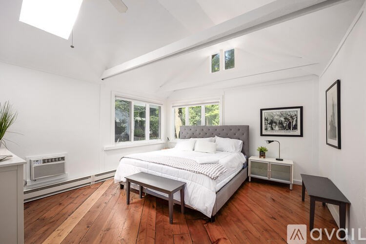 A bedroom with a large bed, a nightstand, and a window.