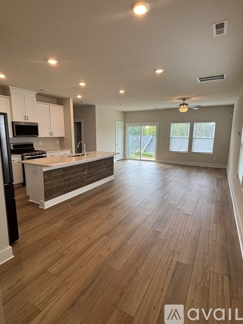 A kitchen with wooden floors and a refrigerator on the left side.