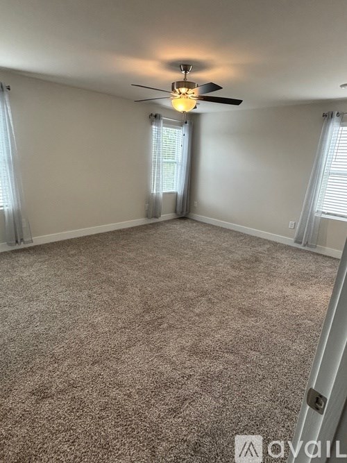 A room with a ceiling fan and carpeted floor.