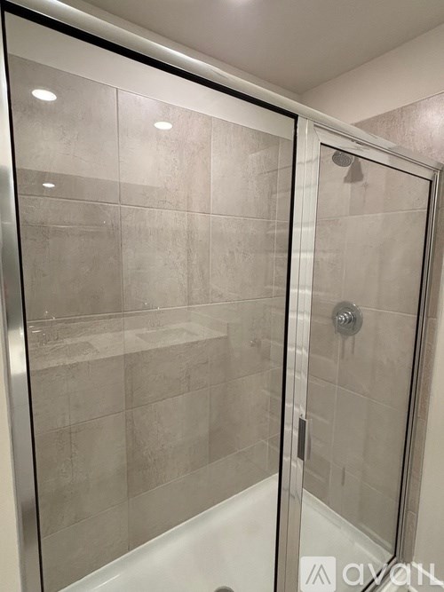 A glass shower door with a silver handle.