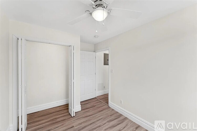 A room with a ceiling fan and a doorway leading to another room.