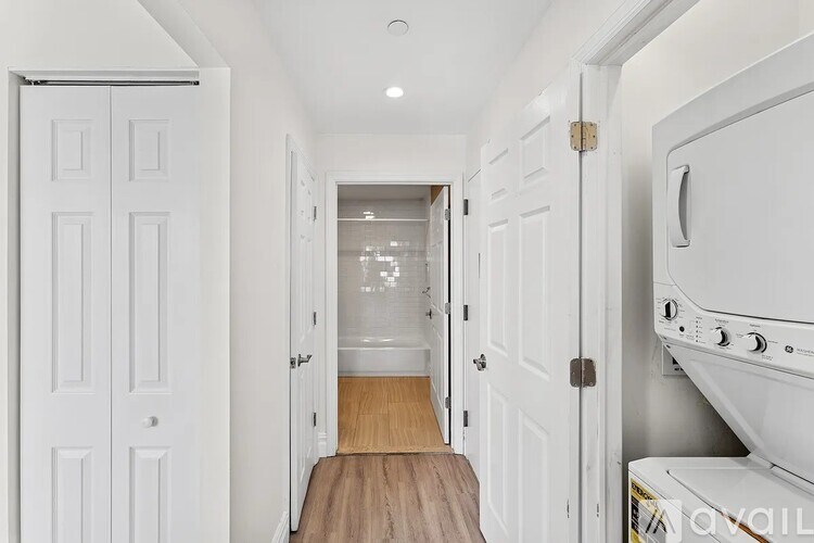 A white door is open to a hallway with a wooden floor.