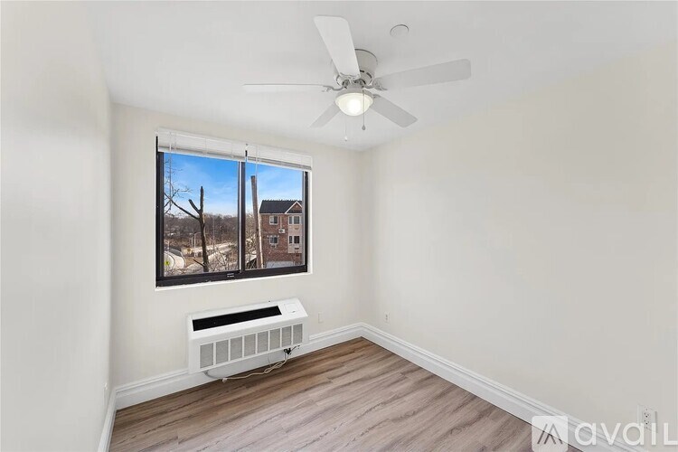 A room with a ceiling fan and a window showing a view of a house.