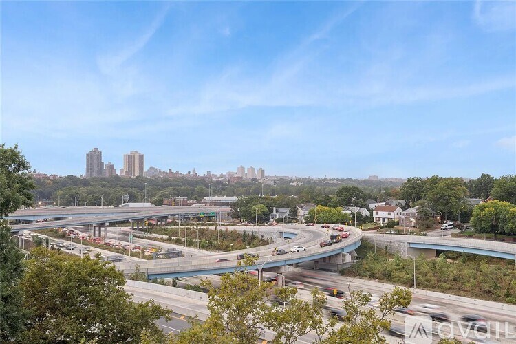 A highway interchange with cars on the road and buildings in the background.