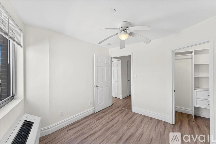 A room with a ceiling fan and a window with an air conditioner unit.
