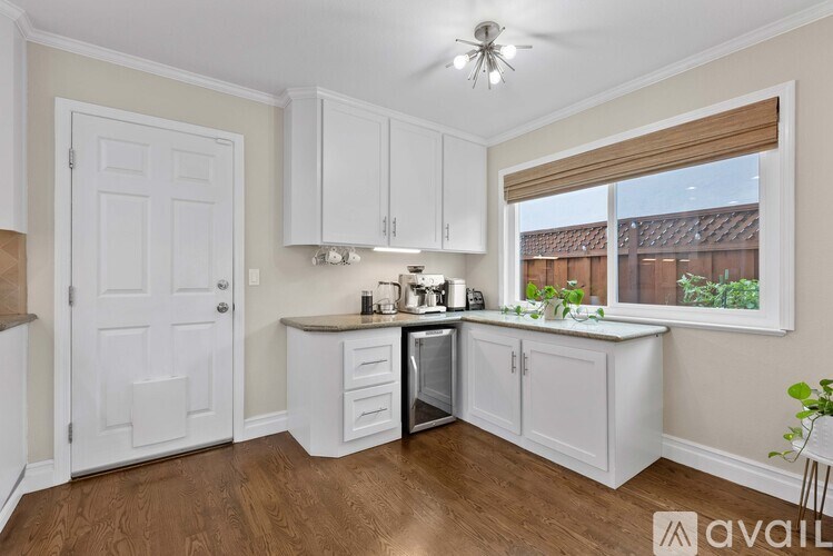 A kitchen with white cabinets and a wooden floor.