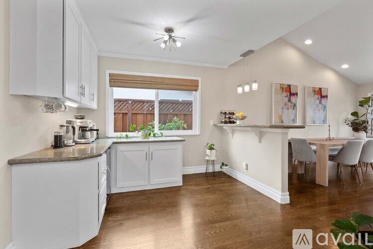 A kitchen with white cabinets and a wooden floor.