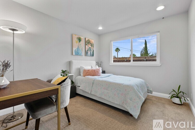 A bedroom with a bed, a desk, and a window showing an outdoor view.