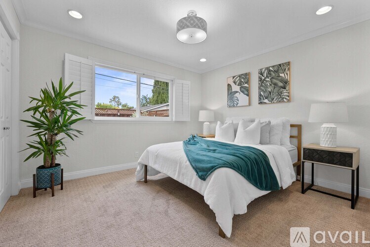 A bedroom with a large bed and a potted plant.
