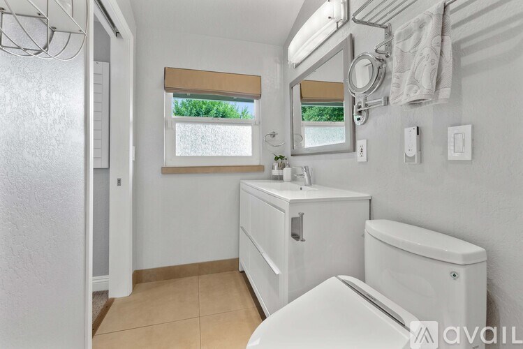 A bathroom with a toilet, sink, and mirror.